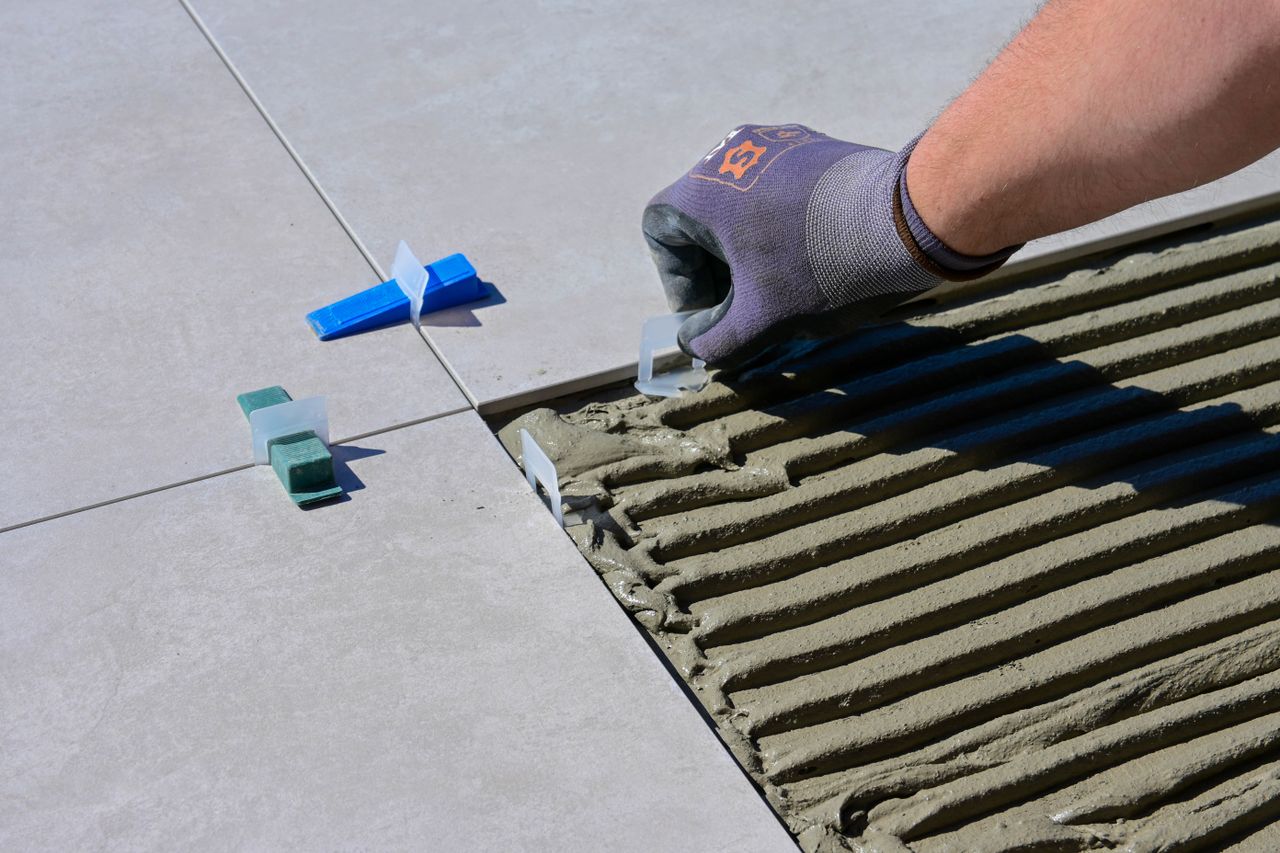 Crafting Captivating Headlines: Your awesome post title goes here Detailed view of gloved hand aligning tiles with levelers and spacers during construction.