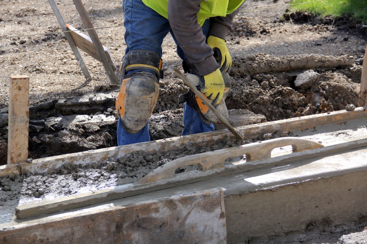 The Art of Drawing Readers In: Your attractive post title goes here Worker using a trowel to smooth concrete at an outdoor construction site.