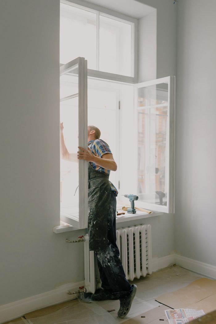 Mastering the First Impression: Your intriguing post title goes here Side view of anonymous handyman in uniform mounting window frame during renovation process in flat