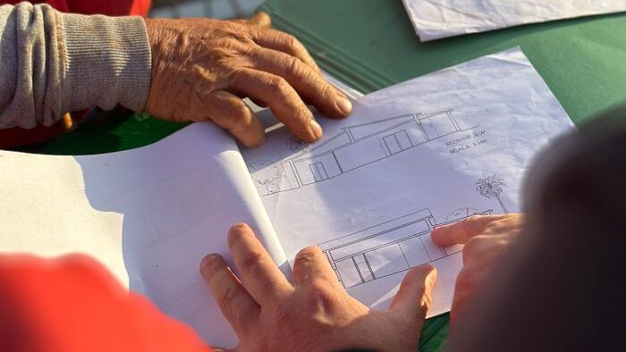A team of architects examining architectural blueprints at an outdoor construction site.